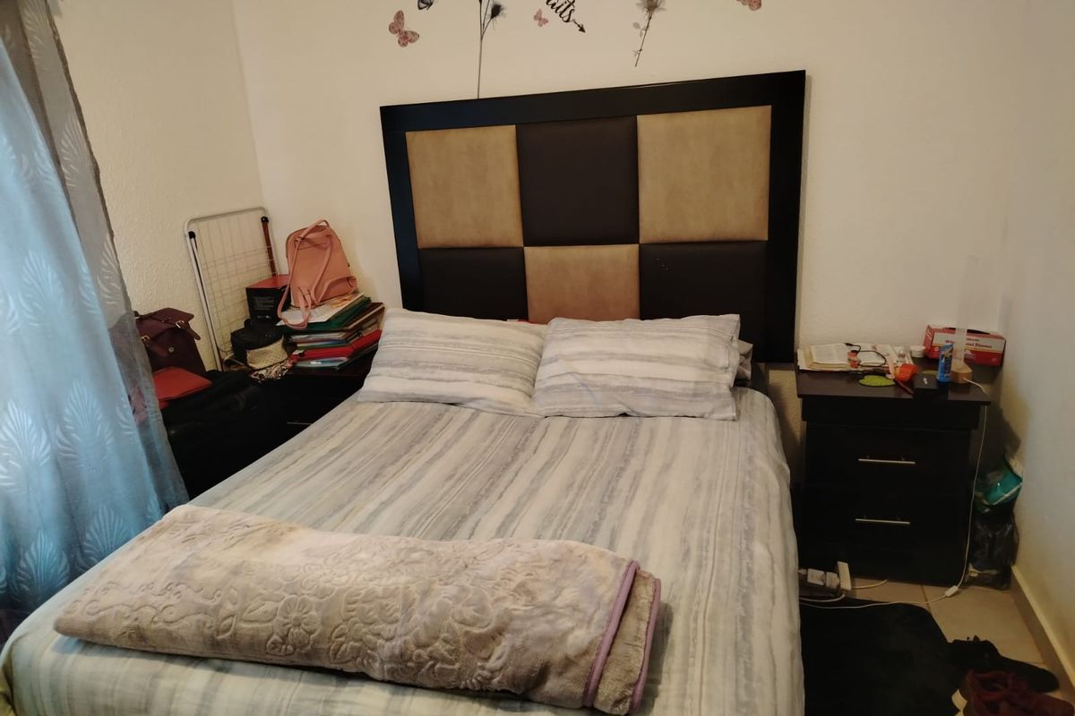 A functional bedroom featuring a built-in headboard and tiled flooring, providing a comfortable and practical sleeping space.