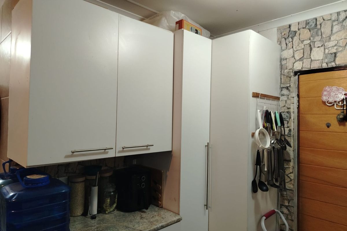 A functional kitchen area featuring white cabinetry, stone-effect wall cladding, and stone-look countertops, providing practical storage and workspace.