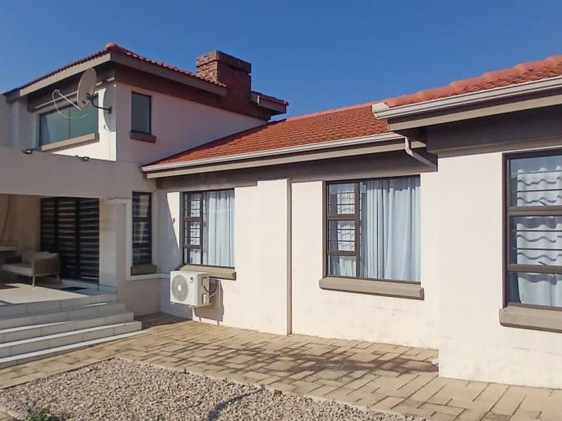 Rear view of the property featuring a covered patio area, tiled steps, and paved outdoor space with established roof structure.