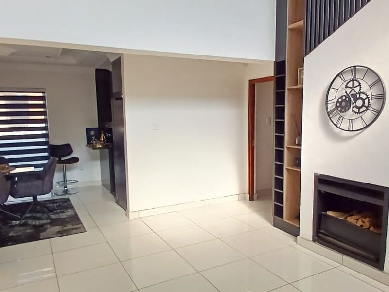 Open plan living area featuring a modern built-in fireplace, tiled flooring, and integrated shelving, seamlessly connecting to the dining space.