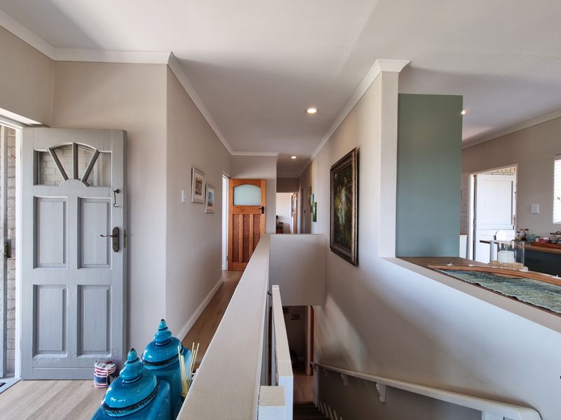 A bright, well-maintained hallway featuring a staircase, recessed lighting, and neutral wall finishes, providing access to multiple rooms within the home.