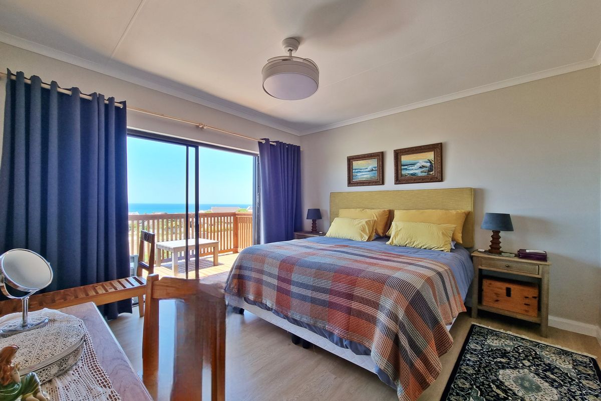 Spacious bedroom featuring laminate flooring, a ceiling fan, and large sliding glass doors opening onto a private balcony with ocean views.