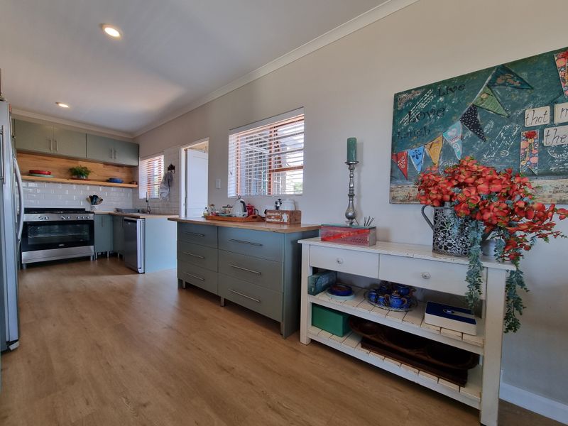 A well-maintained kitchen featuring sage green cabinetry, subway tile backsplash, wooden countertops, and a modern gas stove with an integrated oven.