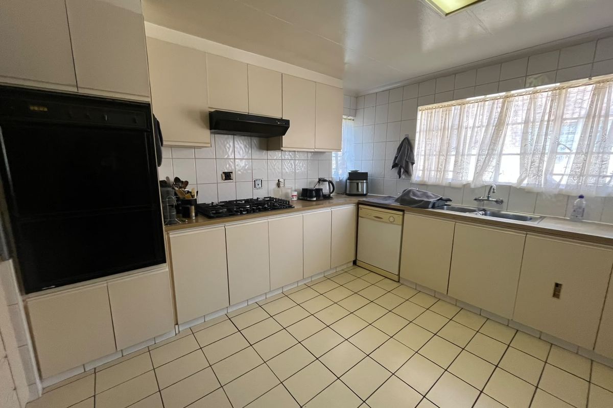 A functional kitchen featuring built-in cabinetry, a gas hob, integrated oven, and tiled flooring, offering a classic layout ready for modernization.