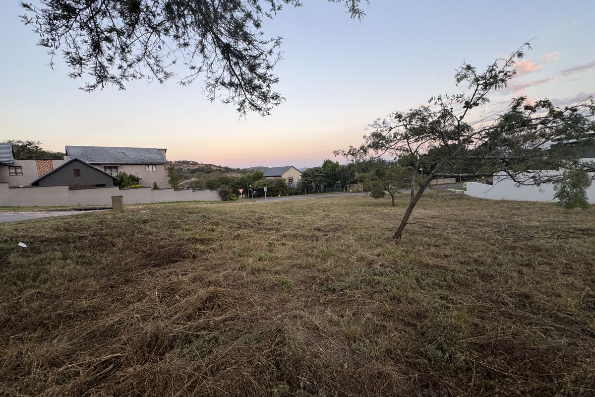 A view of a vacant residential plot of land with surrounding neighborhood houses visible in the background.