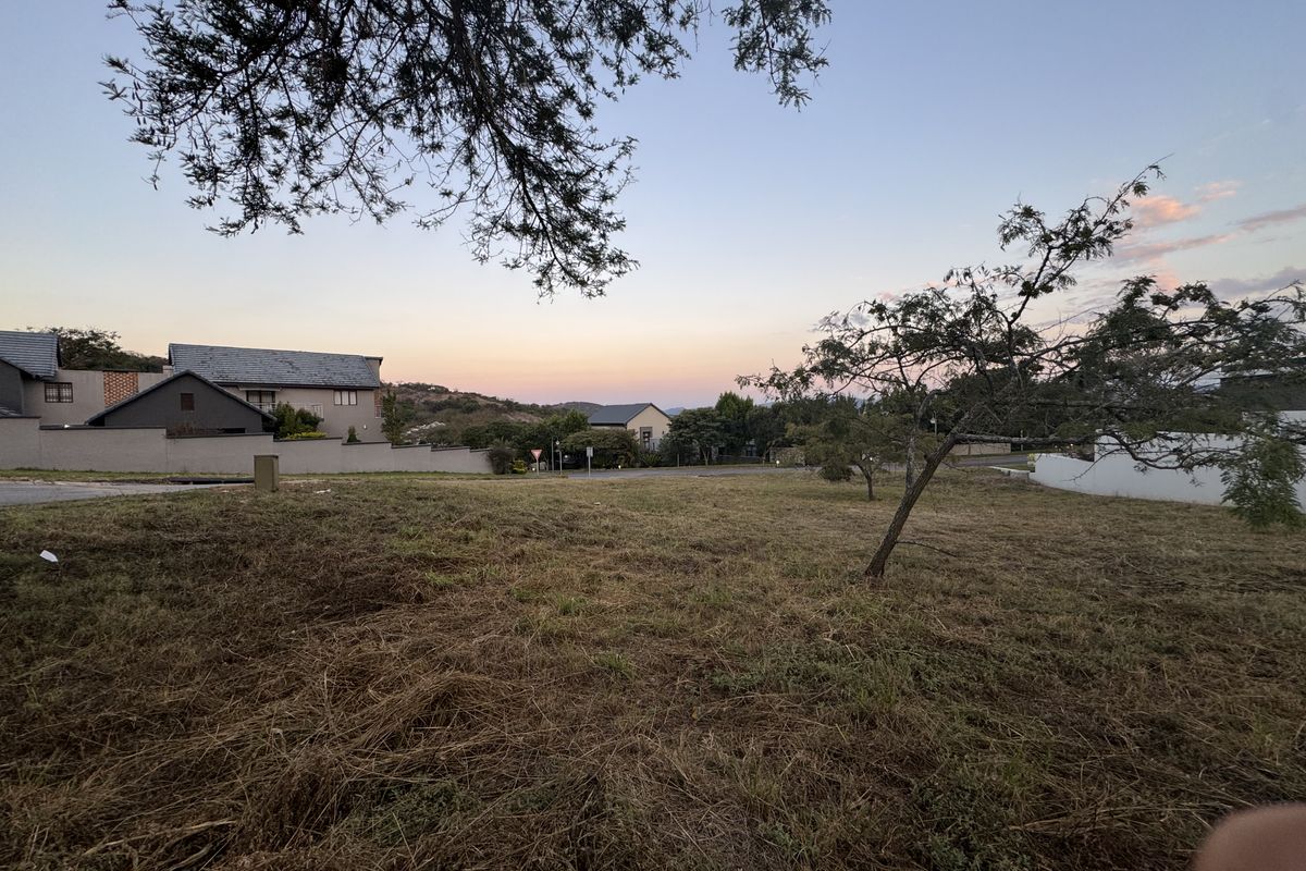 A view of a vacant residential plot of land with surrounding neighborhood houses visible in the background.
