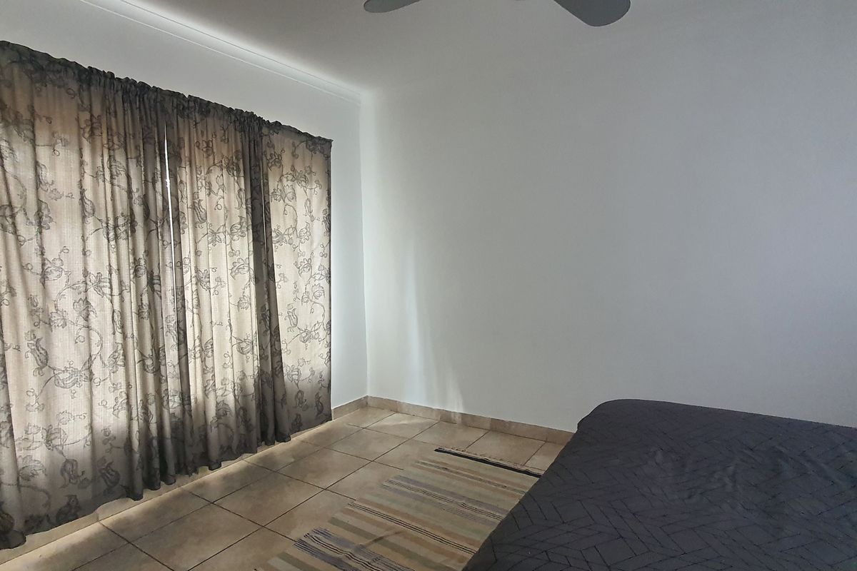 A bedroom featuring tiled flooring and a ceiling fan, offering a neutral space ready for personalization.