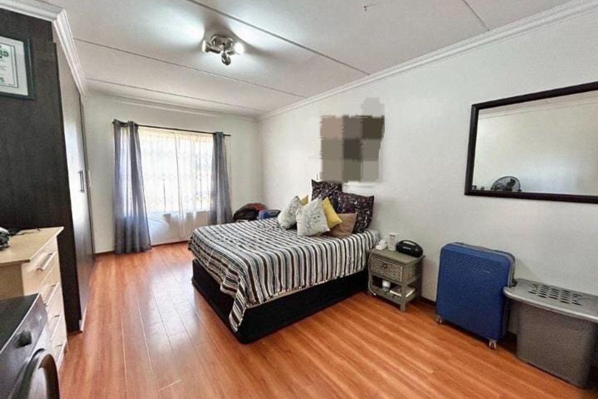 Spacious bedroom featuring laminate flooring, crown molding, and a built-in wardrobe, offering a functional layout with natural light.