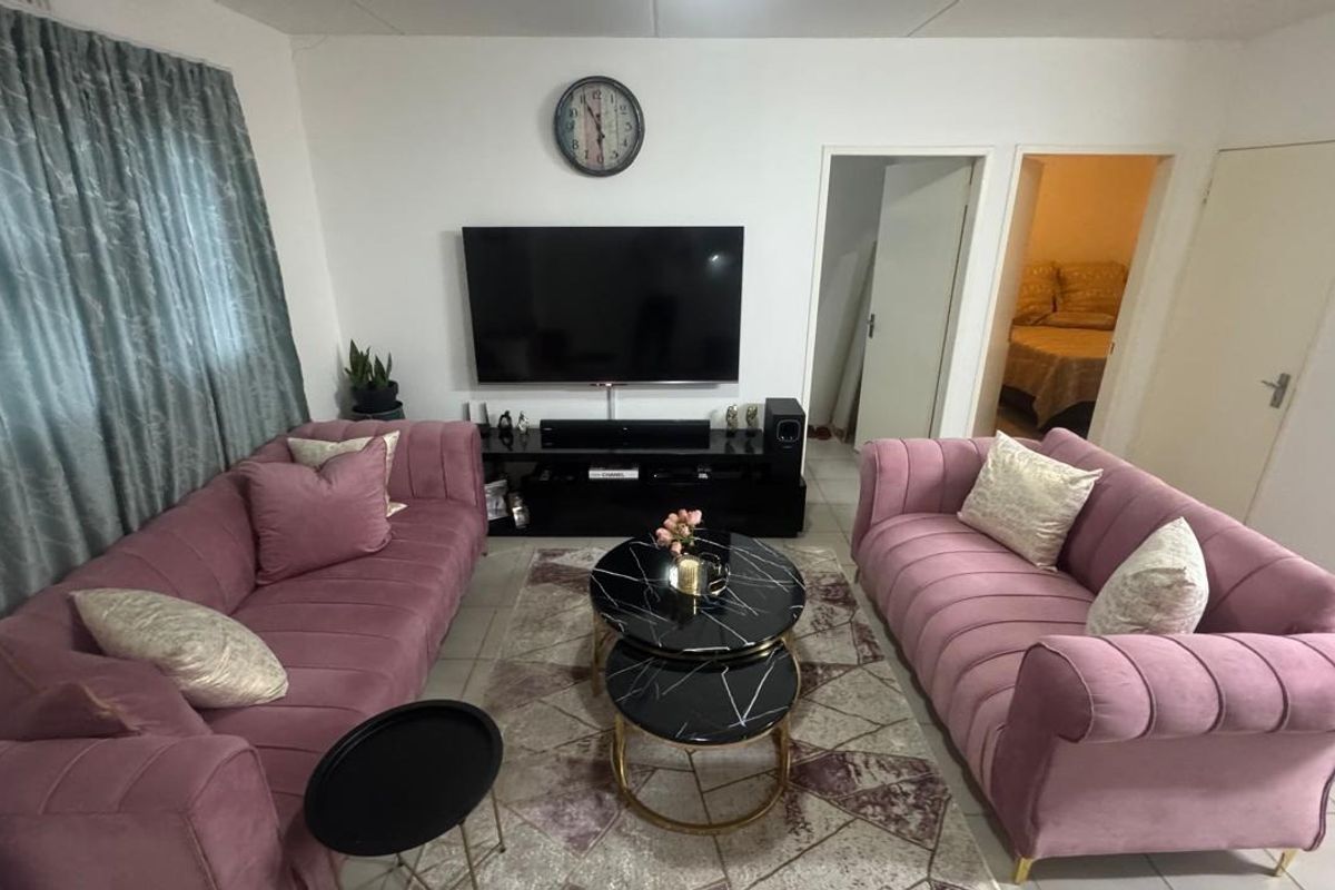 A comfortable living room featuring tiled flooring and access to an adjacent bedroom, providing a functional and well-utilized living space.