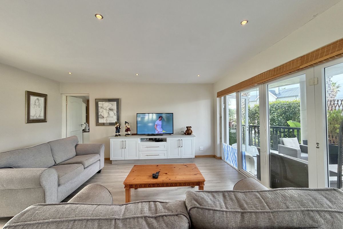 Bright living room featuring laminate flooring, recessed downlights, and large sliding glass doors that provide seamless access to the outdoor patio area.