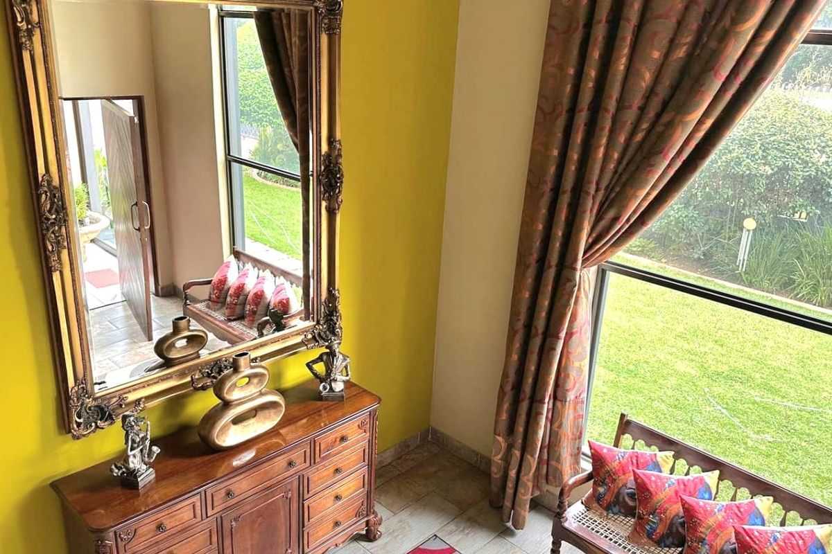 A bright living area featuring large windows with garden views and tiled flooring, offering a pleasant and well-lit space.