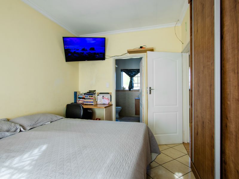 A bedroom featuring tiled flooring, a built-in wardrobe, and direct access to an en-suite bathroom.