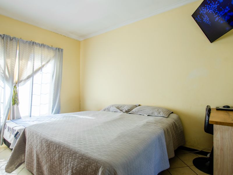 A standard bedroom featuring tiled flooring and neutral wall finishes, offering a functional space with natural light from the window.