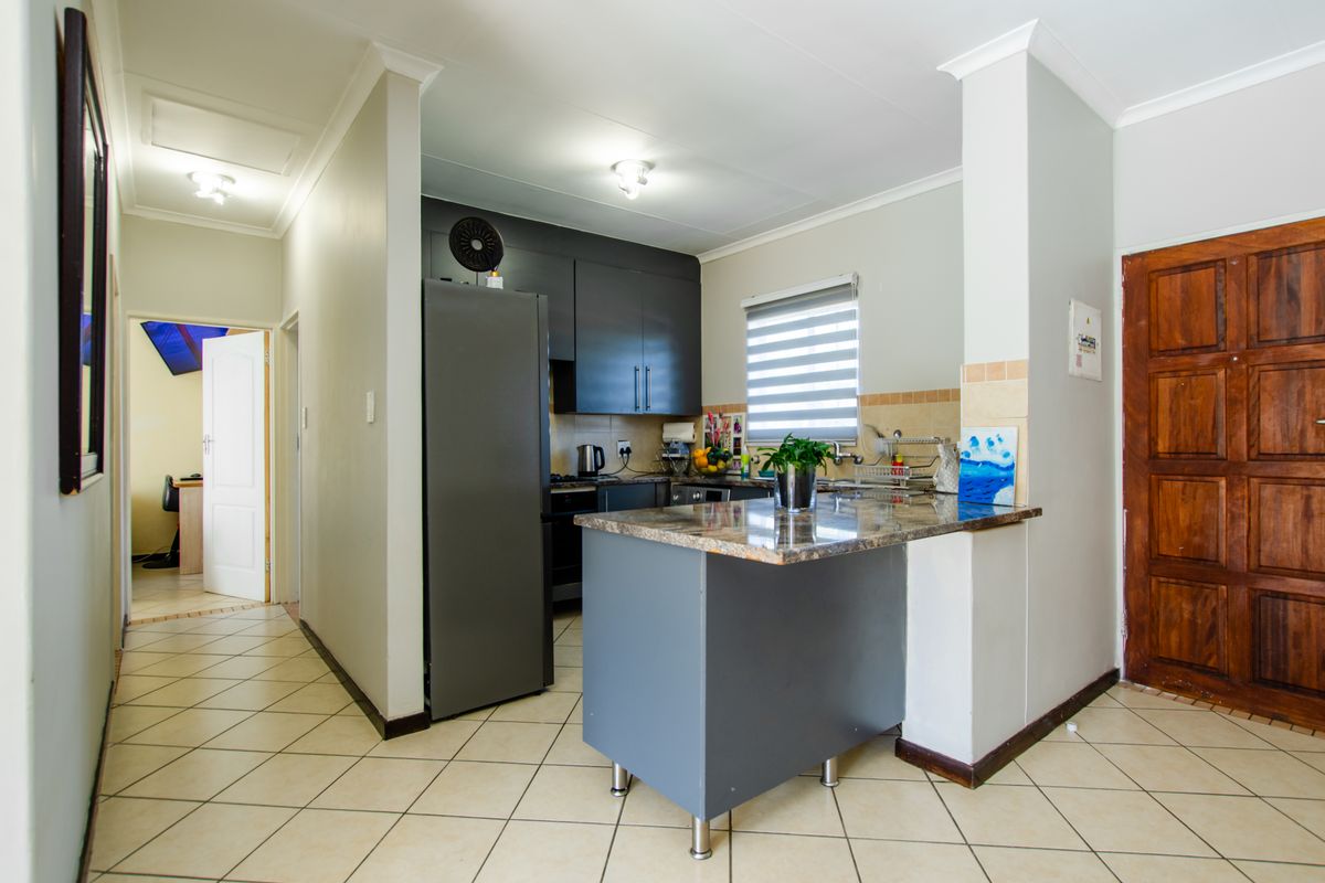 A functional kitchen featuring dark cabinetry, granite countertops, a breakfast bar, and tiled flooring, with a convenient layout and neutral wall finishes.