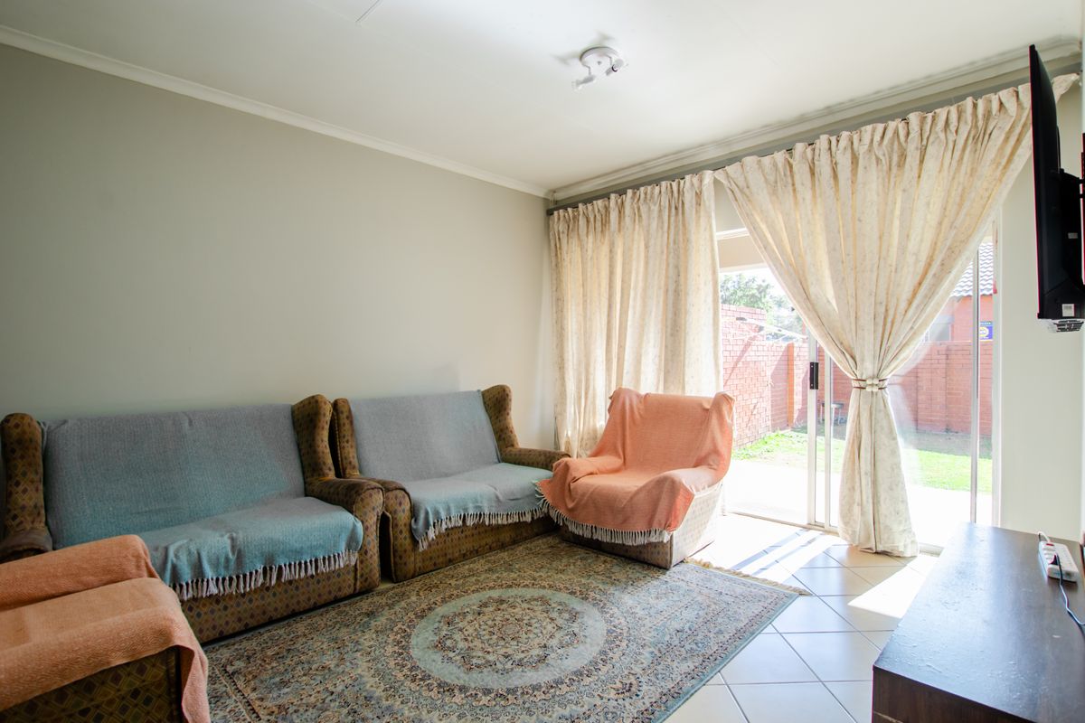 A living room featuring tiled flooring and a sliding glass door providing access to the rear garden area.