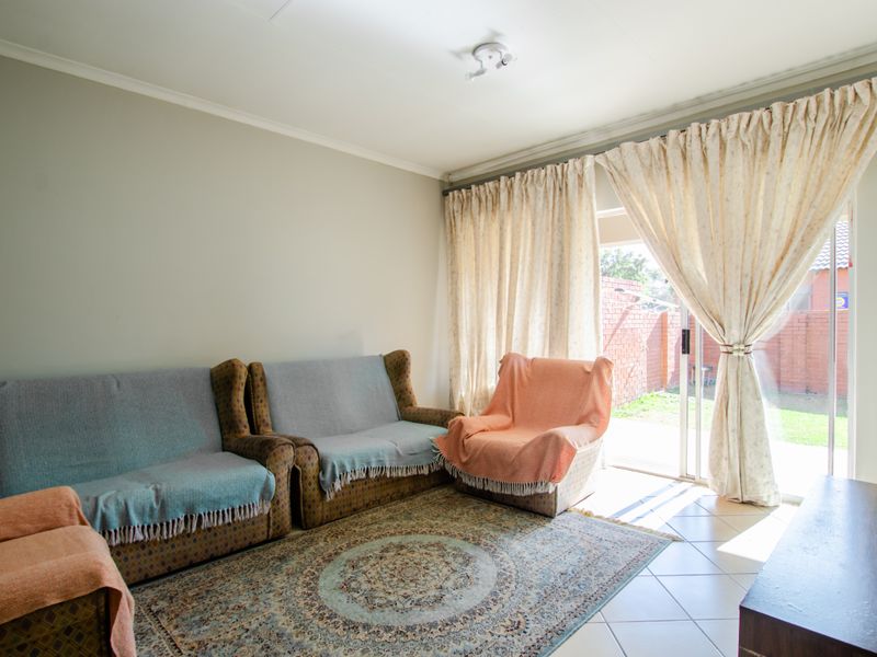 A living room featuring tiled flooring and a sliding glass door providing access to the rear garden area.