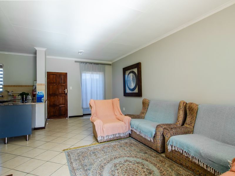 Open plan living area featuring tiled flooring and a functional kitchen with granite countertops, seamlessly connecting to the main entrance.