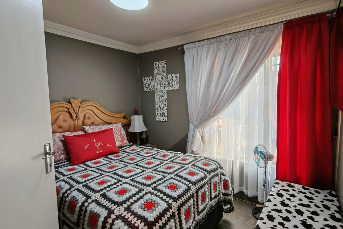 A cozy bedroom featuring crown molding and tiled flooring, offering a comfortable space with natural light from the window.
