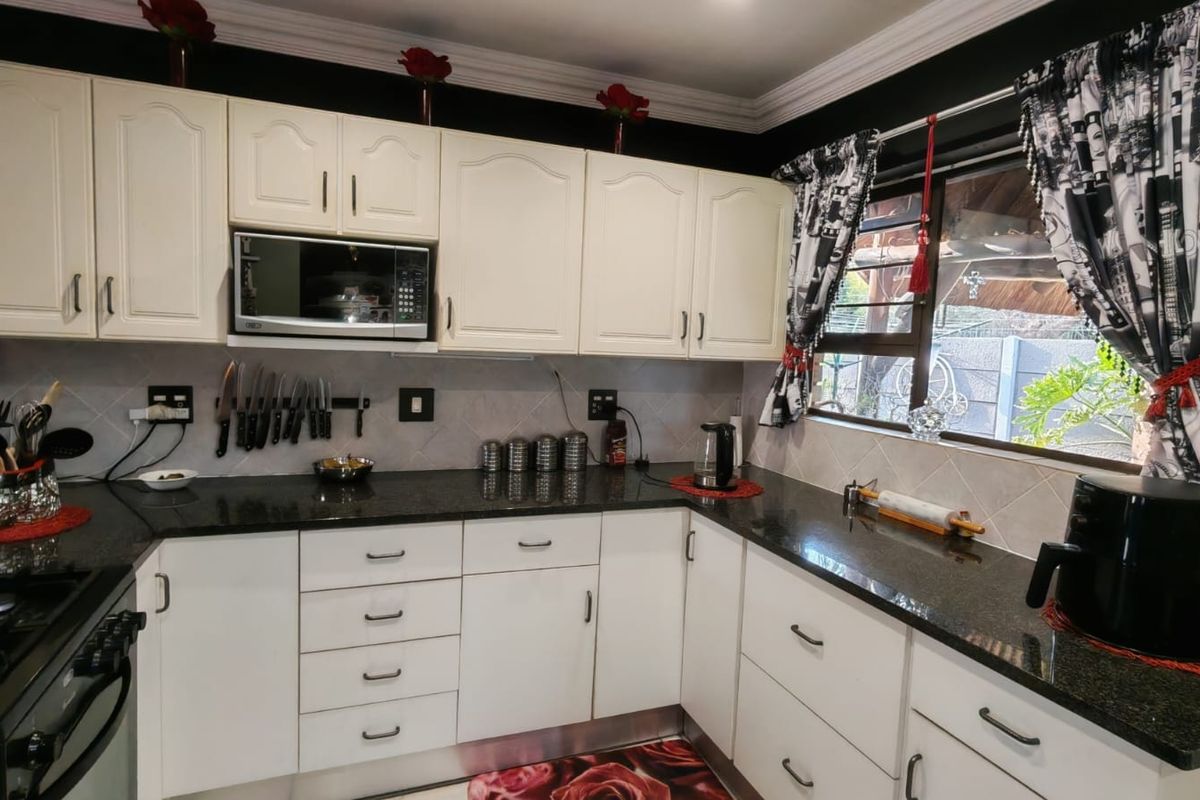 A functional kitchen featuring white cabinetry, dark granite countertops, a tiled backsplash, and a built-in microwave, offering a clean and well-maintained workspace.