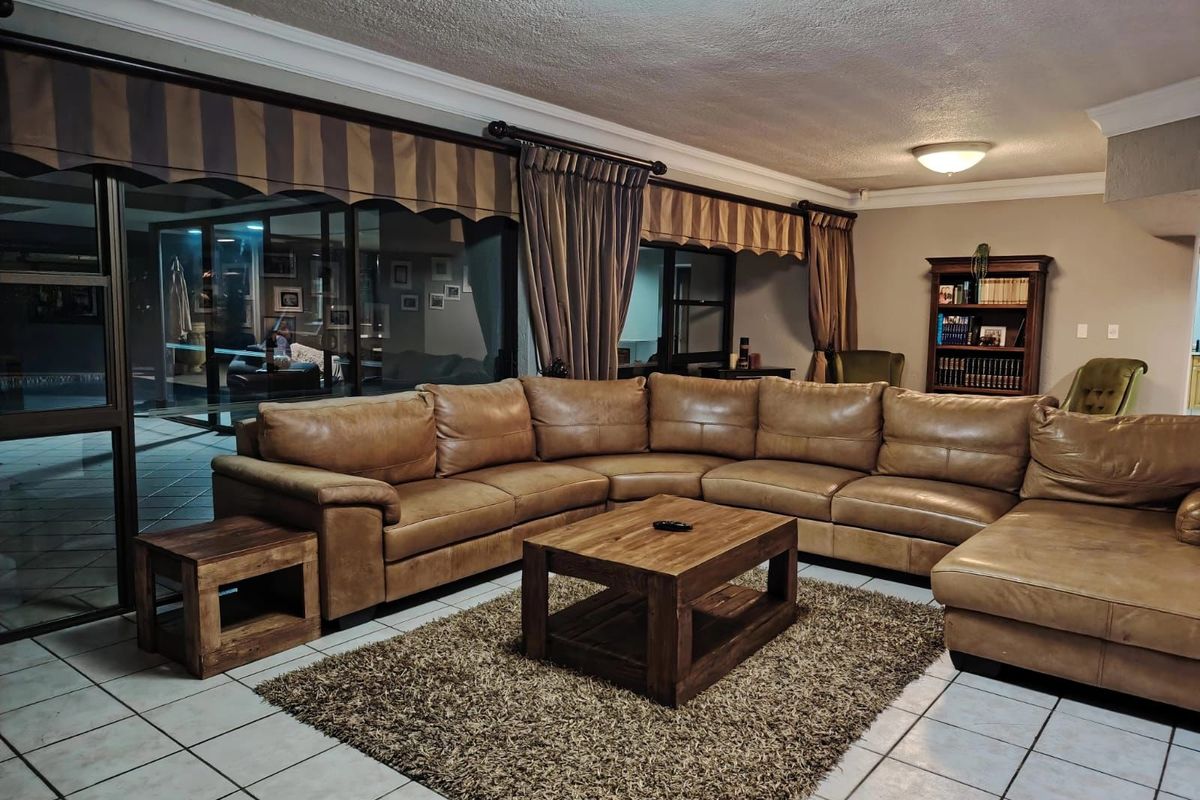 Spacious living room featuring tiled flooring, large sliding glass doors providing outdoor access, and a built-in shelving unit.