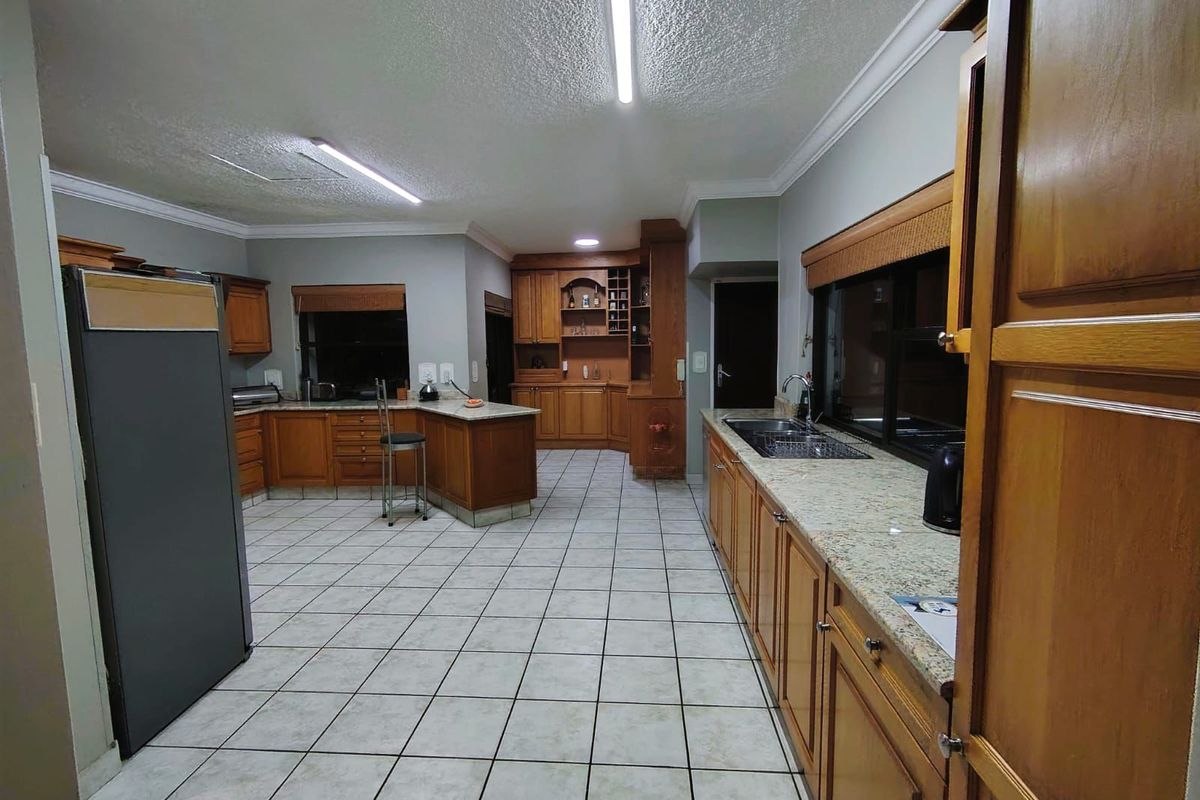 Spacious kitchen featuring extensive wooden cabinetry, granite countertops, double sink, and tiled flooring with ample storage and workspace.