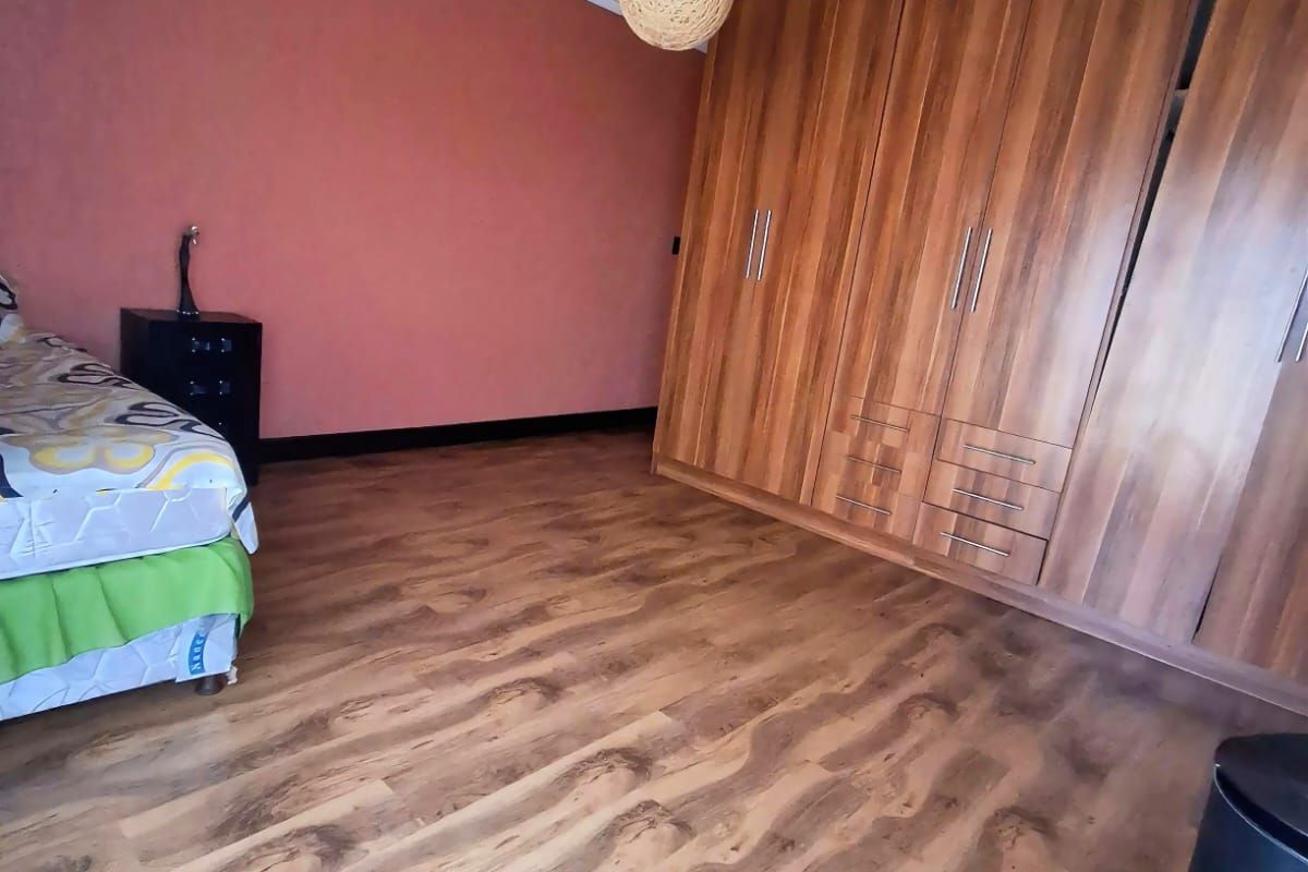 Bedroom featuring built-in wooden cabinetry, laminate flooring, and decorative ceiling rose.