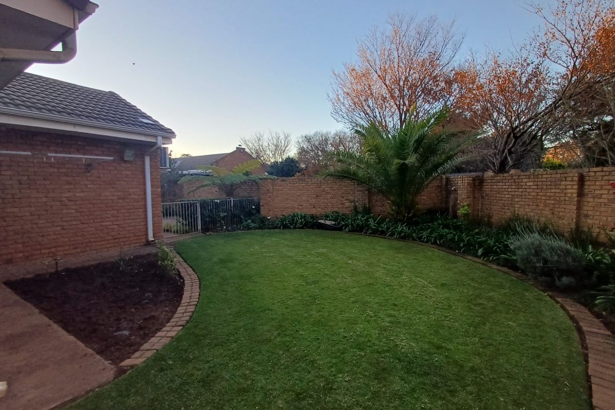 A private rear garden featuring a well-maintained lawn, brick boundary walls, and established landscaping, providing a peaceful outdoor space.