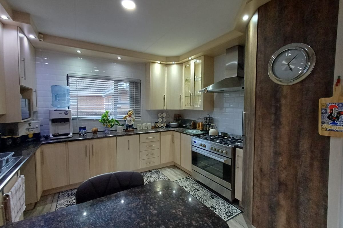A well-appointed kitchen featuring light wood cabinetry, granite countertops, a stainless steel gas stove with extractor fan, and subway tile backsplash.