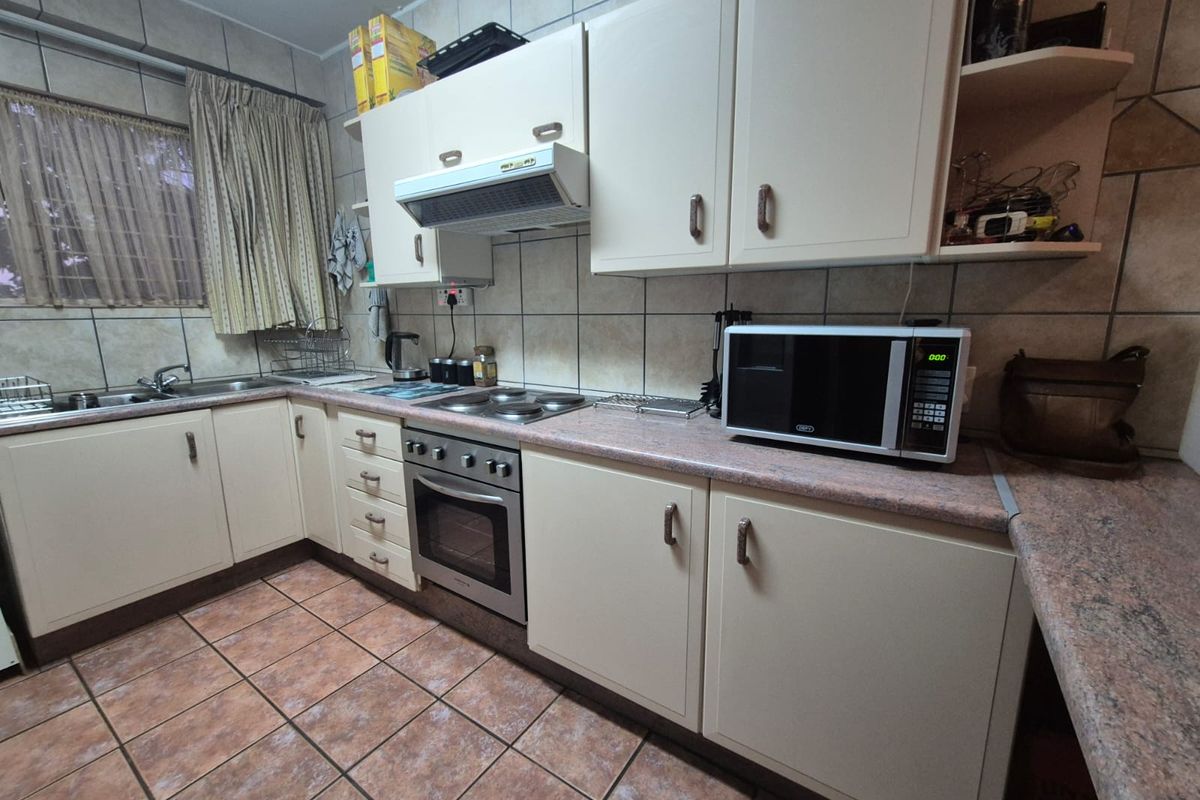 A functional kitchen featuring built-in cabinetry, a fitted oven and hob, extractor fan, and tiled splashbacks.