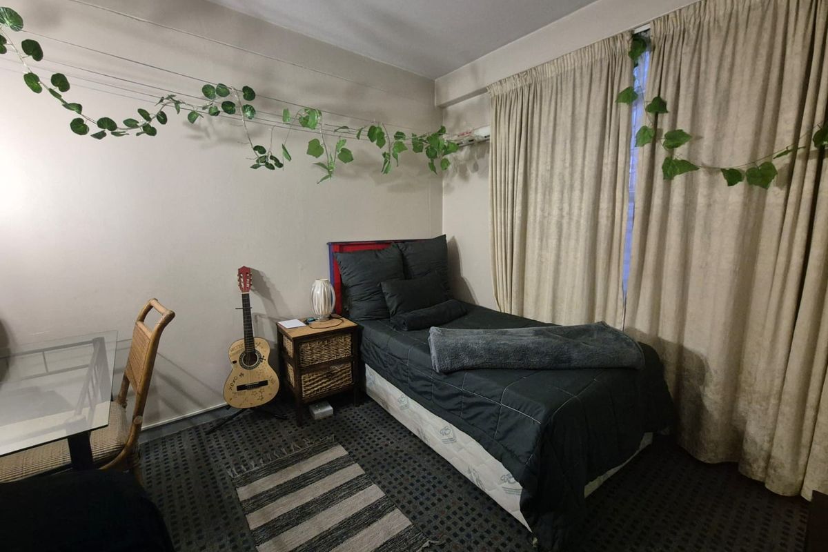 A bedroom featuring neutral walls, carpeted flooring, and floor-to-ceiling curtains covering the window.