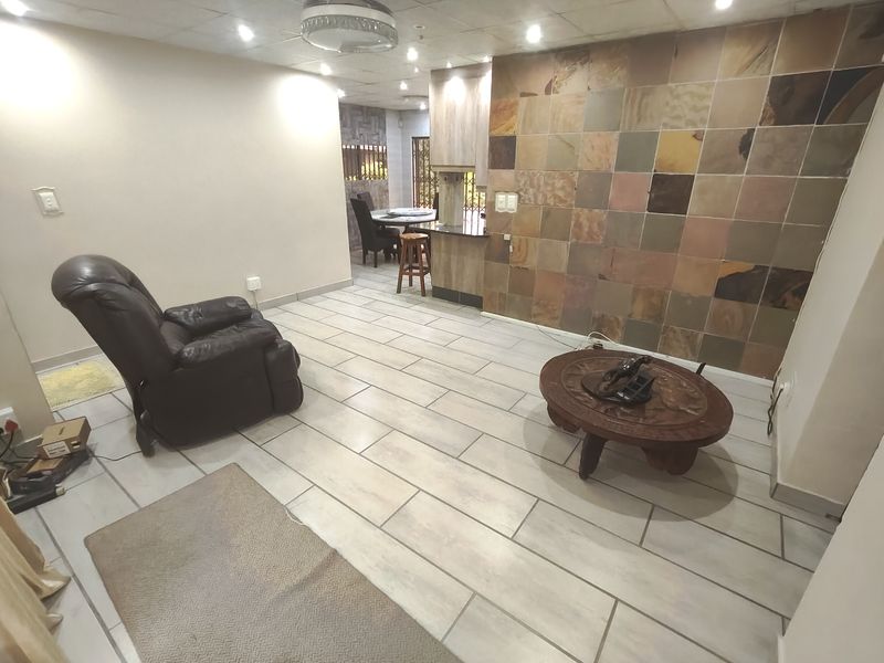 Open plan living area featuring a stone accent wall, tiled flooring, and a breakfast bar connecting to the kitchen space.