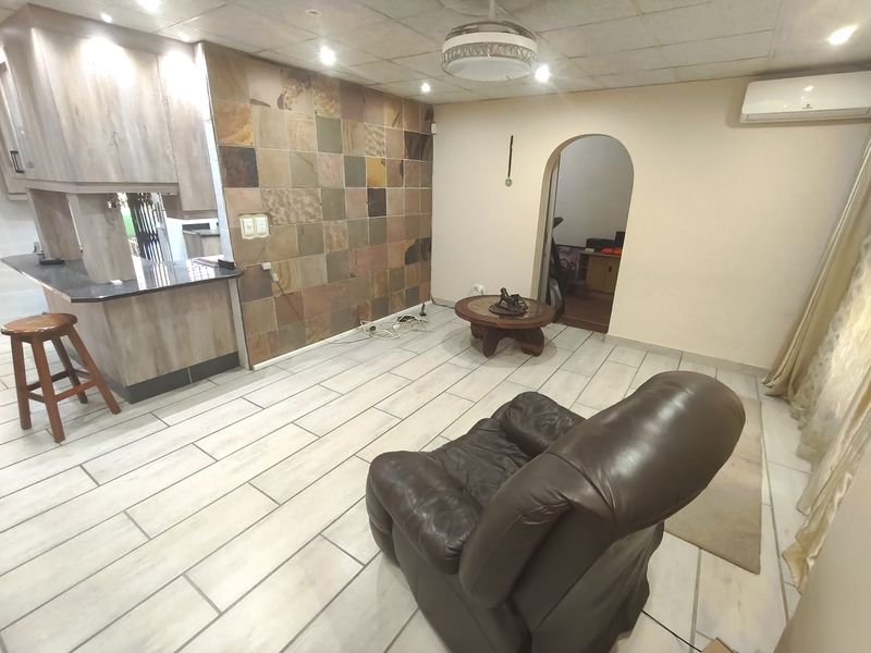 Open plan living area featuring a stone tile accent wall, granite breakfast bar, ceramic floor tiles, and an arched doorway leading to adjacent rooms.