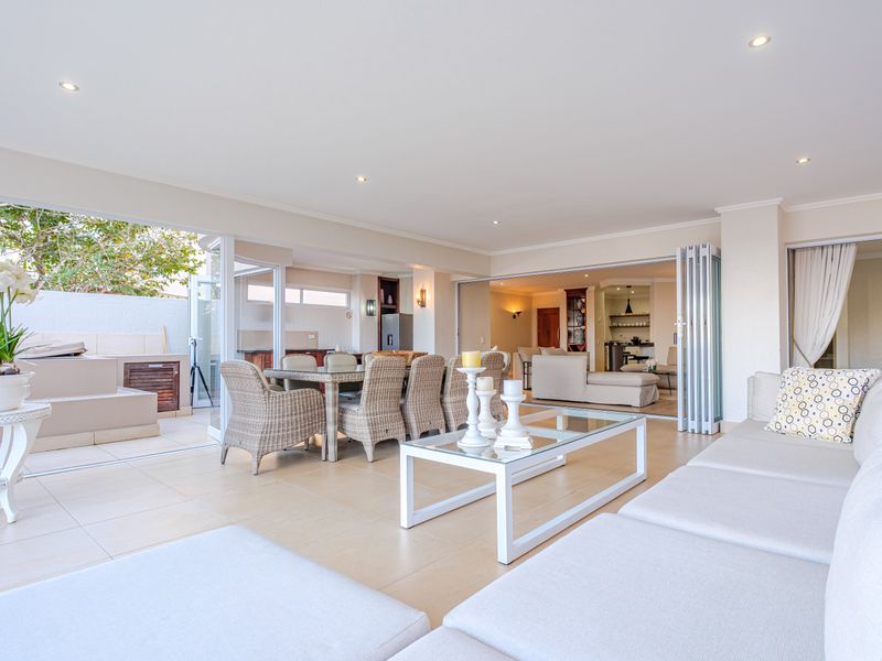 Spacious covered patio featuring tiled flooring, recessed lighting, and stacking glass doors that open to an integrated outdoor braai area.