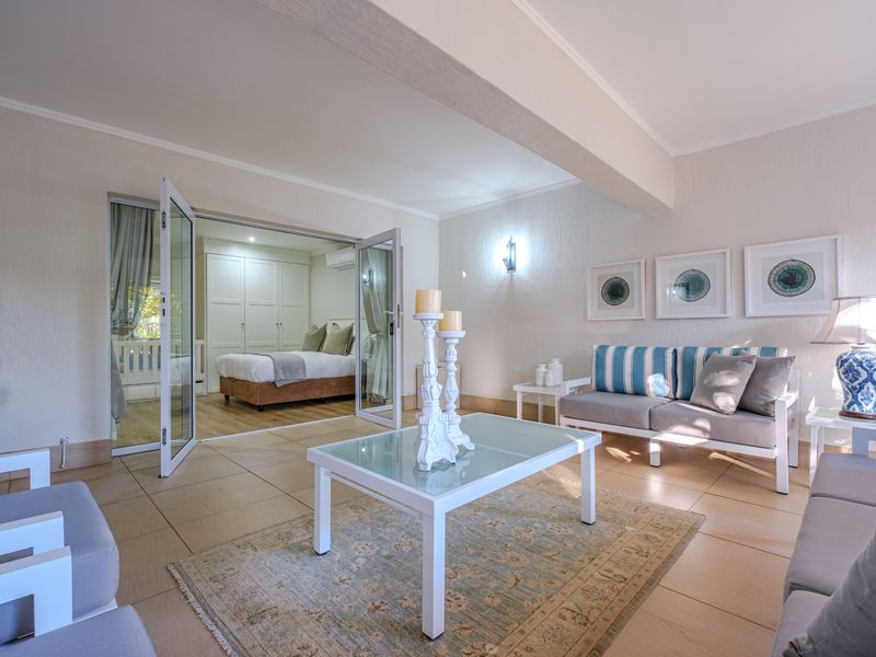 A bright living room featuring tiled floors and french doors opening into a bedroom with built-in storage.
