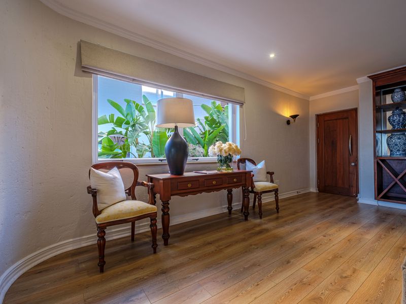A well-maintained living area featuring warm laminate flooring, a built-in wooden display unit, and natural light through a large window.