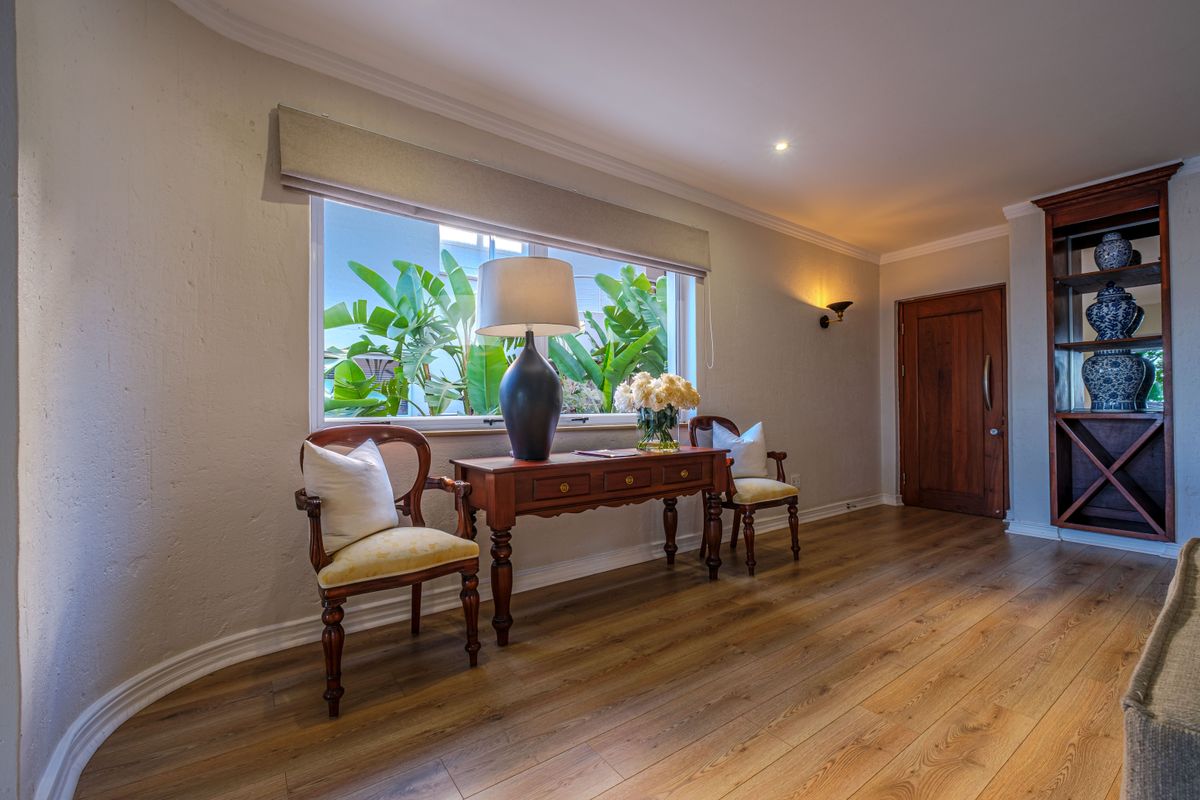 A well-maintained living area featuring warm laminate flooring, a built-in wooden display unit, and natural light through a large window.