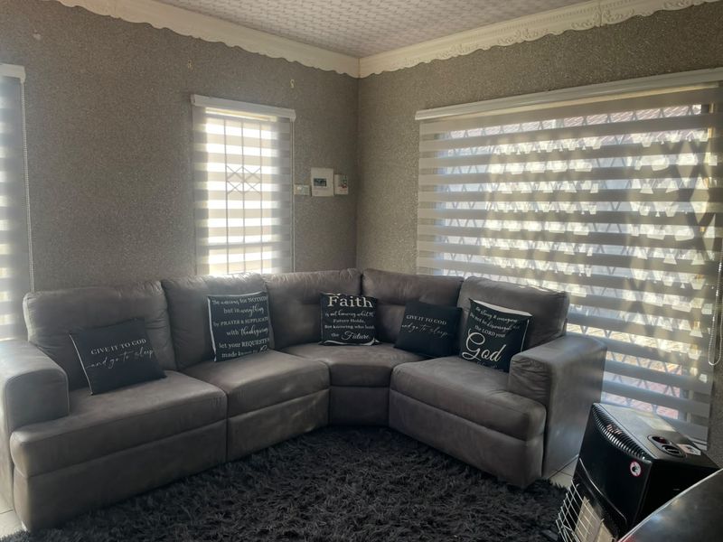 A living room featuring textured wallpaper, decorative cornice detailing, and modern zebra blinds, providing a neutral base for interior updates.