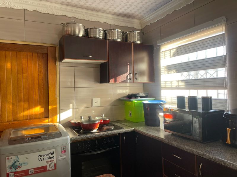 A functional kitchen featuring dark wood cabinetry, granite countertops, a built-in oven with hob, and tiled wall finishes.