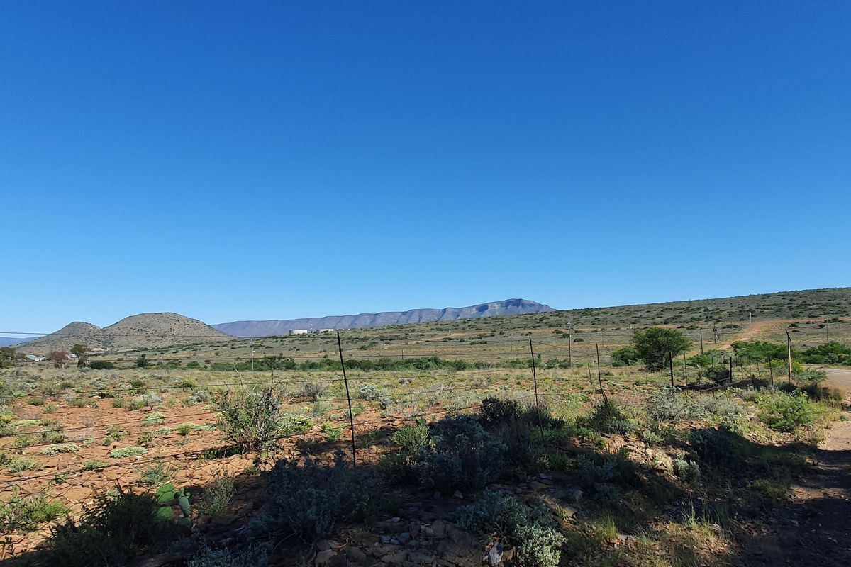 A wide-angle view of the vacant residential land featuring natural landscape, native vegetation, and distant mountain ranges.