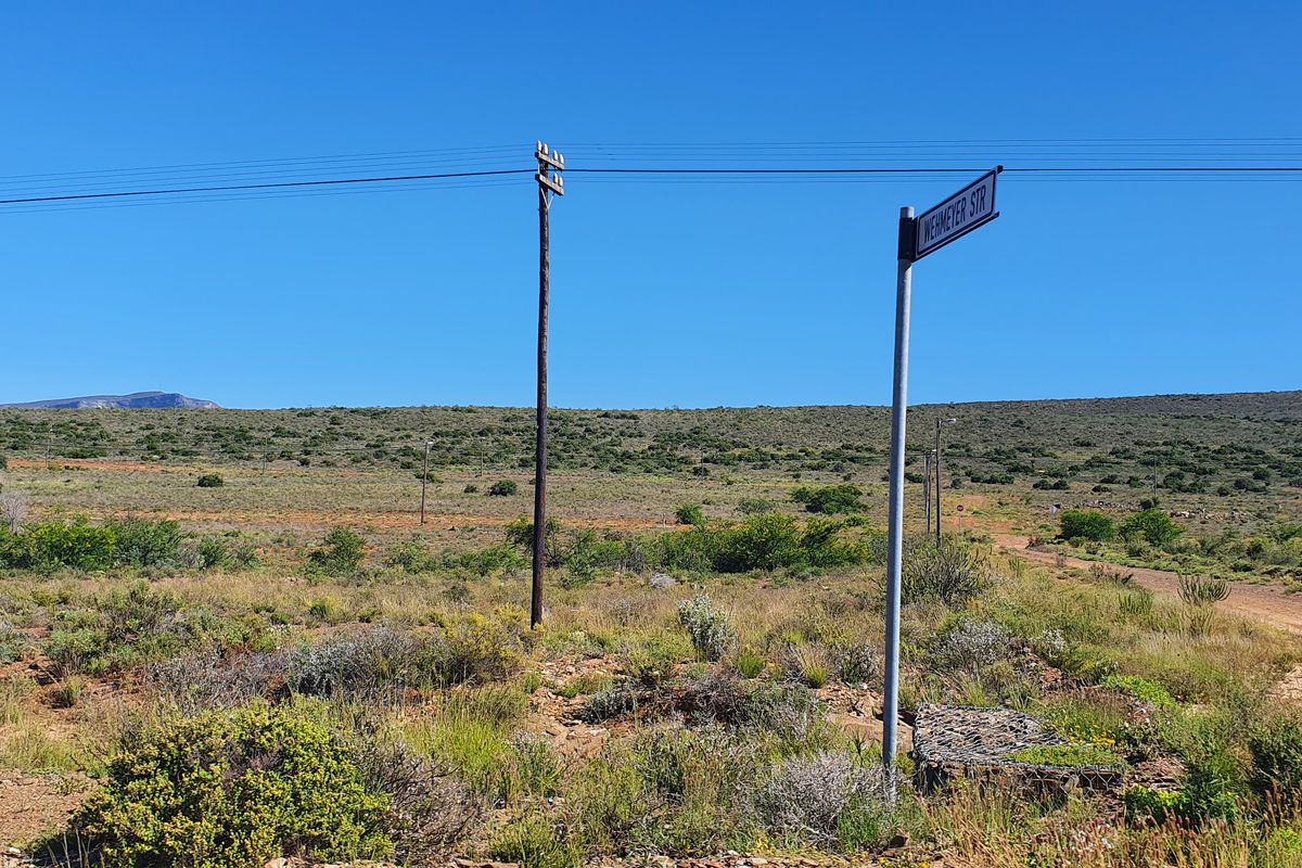 A view of the vacant residential land showing the street access, utility poles, and surrounding natural landscape.