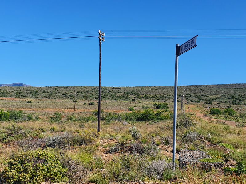 A view of the vacant residential land showing the street access, utility poles, and surrounding natural landscape.