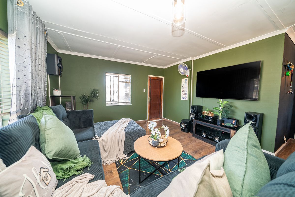 A cozy living room featuring laminate flooring, olive green walls, and a timber door, providing a comfortable and functional space for relaxation.