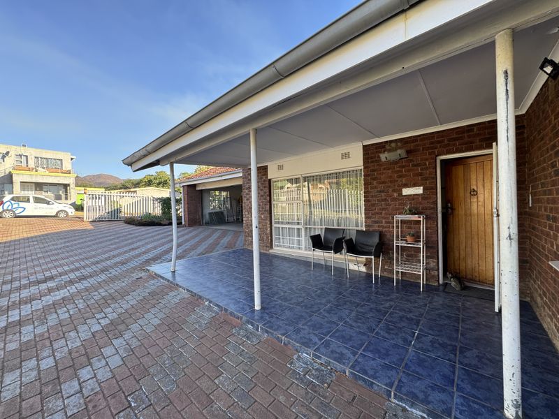 Front entrance featuring a covered tiled porch, brick facade, and paved driveway leading to a garage.