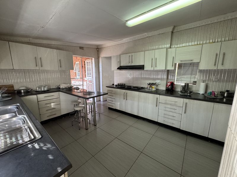 A functional kitchen featuring extensive built-in cabinetry, laminate countertops, a double bowl sink, and a built-in hob with an extractor fan.
