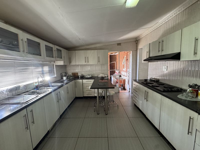 Spacious kitchen featuring extensive built-in cabinetry, a central breakfast island, integrated hob with extractor fan, and tiled flooring throughout.