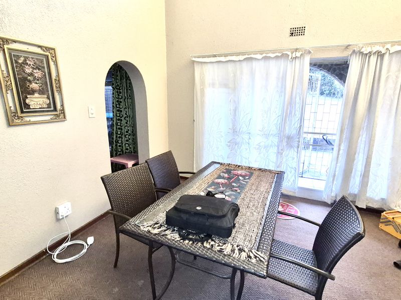 Dining area featuring an arched doorway and sliding glass doors leading to the exterior, with carpet flooring and neutral wall finishes.