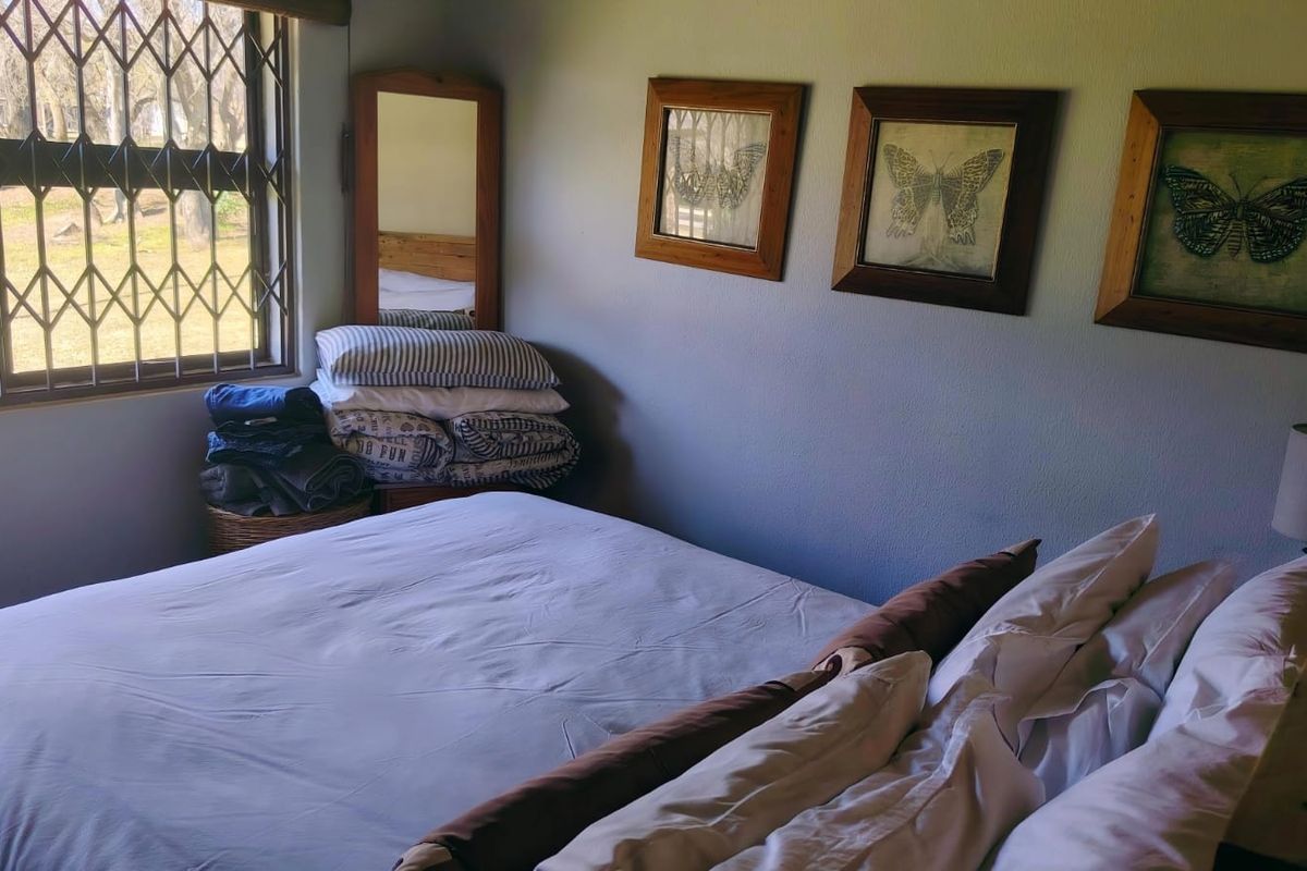 A bedroom featuring a window with a fitted security gate, providing natural light and ventilation.