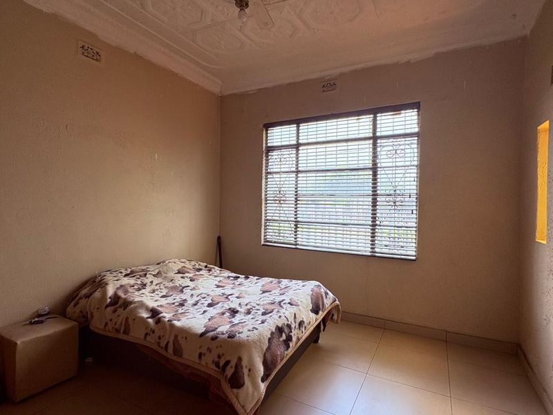 A bedroom featuring tiled flooring, an ornate ceiling, and recessed wall niches. The room requires cosmetic updates to the wall finishes.