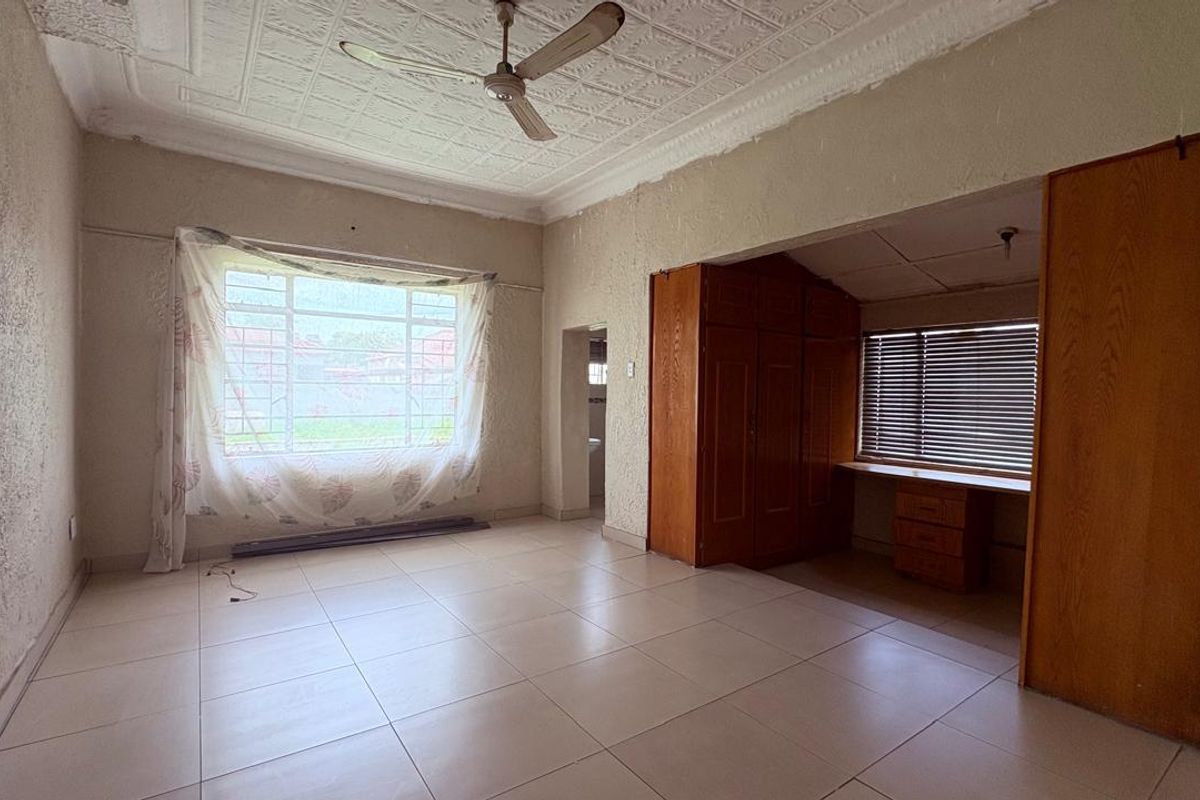 Spacious living area featuring tiled floors, a decorative ceiling with fan, and a dedicated study nook with built-in cabinetry.