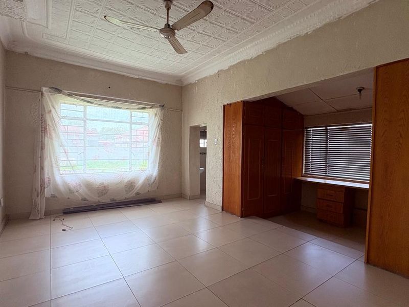 Spacious living area featuring tiled floors, a decorative ceiling with fan, and a dedicated study nook with built-in cabinetry.